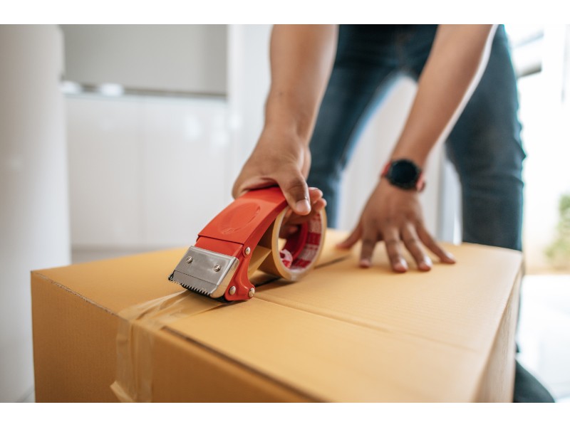Una persona sellando una caja con cinta adhesiva